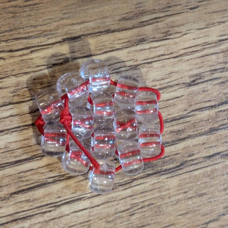 Clear plastic item with red string on a wooden surface