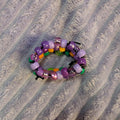 Multicolored beaded ring on a textured gray surface