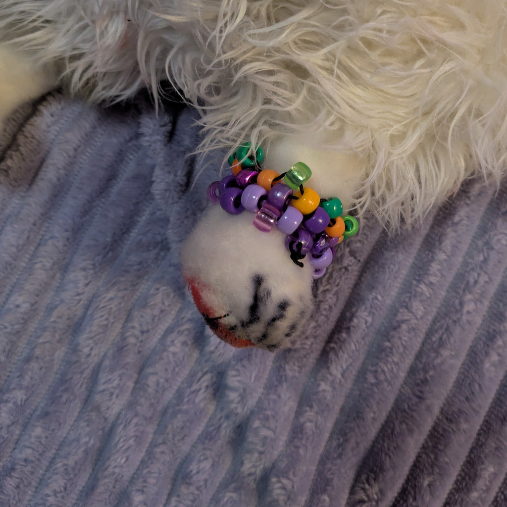 White fluffy dog with colorful beaded toy on a striped fabric background